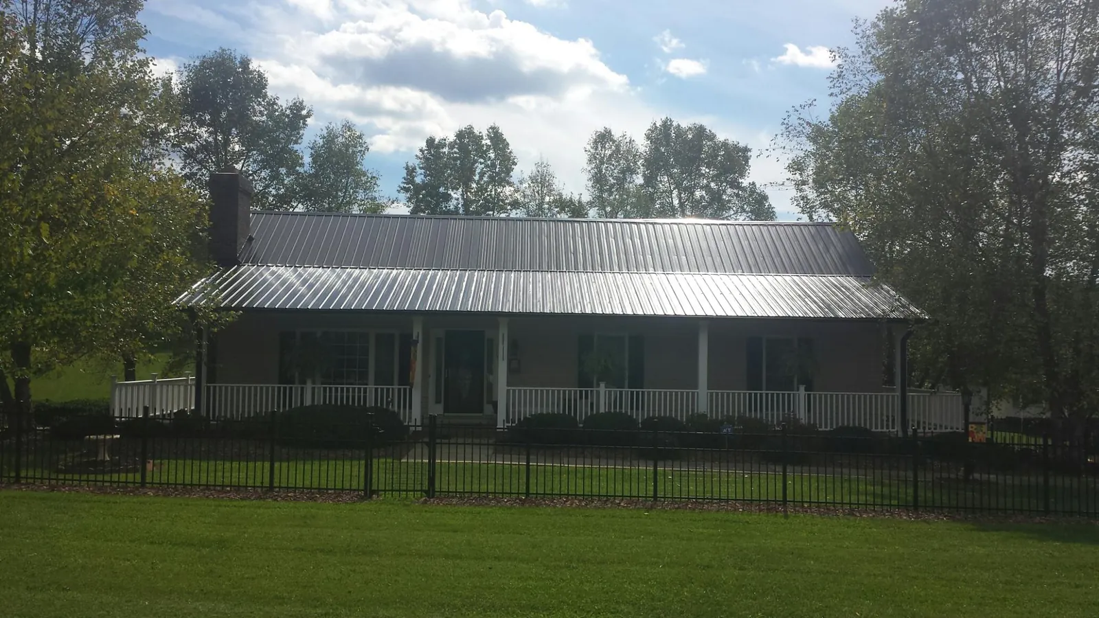 Gray metal roof on a brick ranch with a full width front porch — Gutter Guard Installation work by our crew in Rossburg
