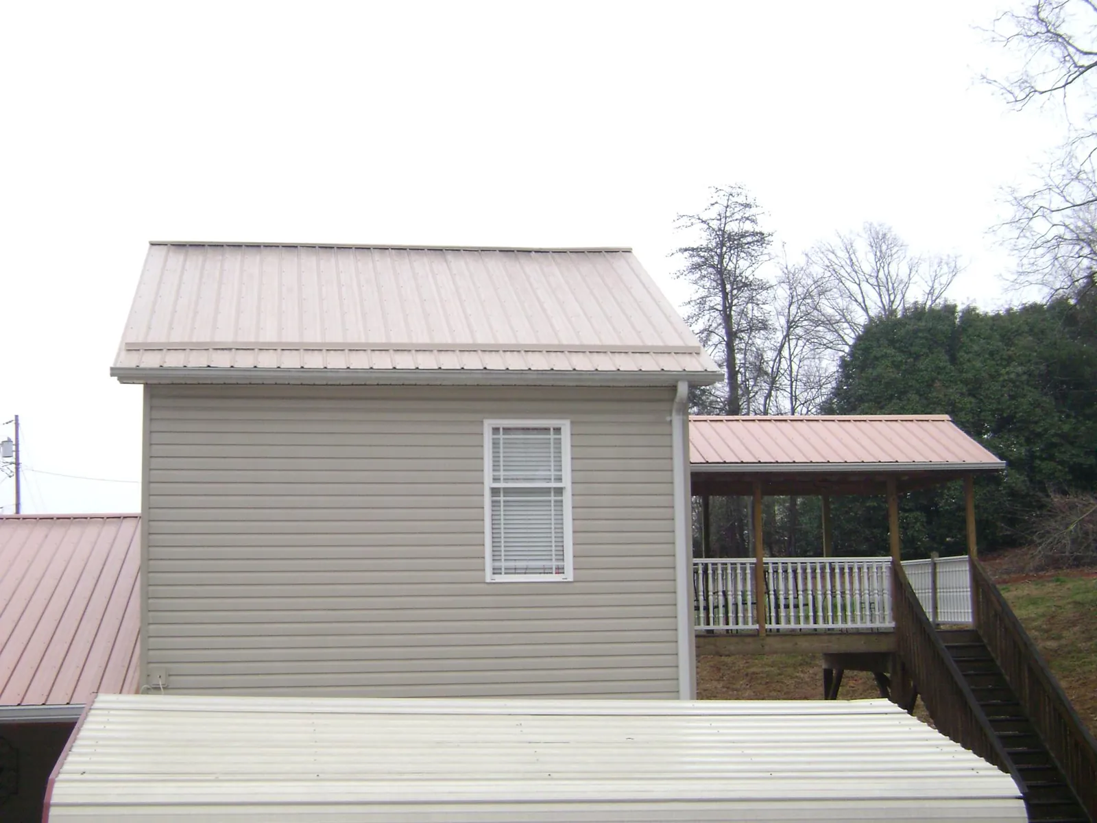 Tan metal roofs on a two story addition and attached porch, from a Roof Replacement job in Rossburg