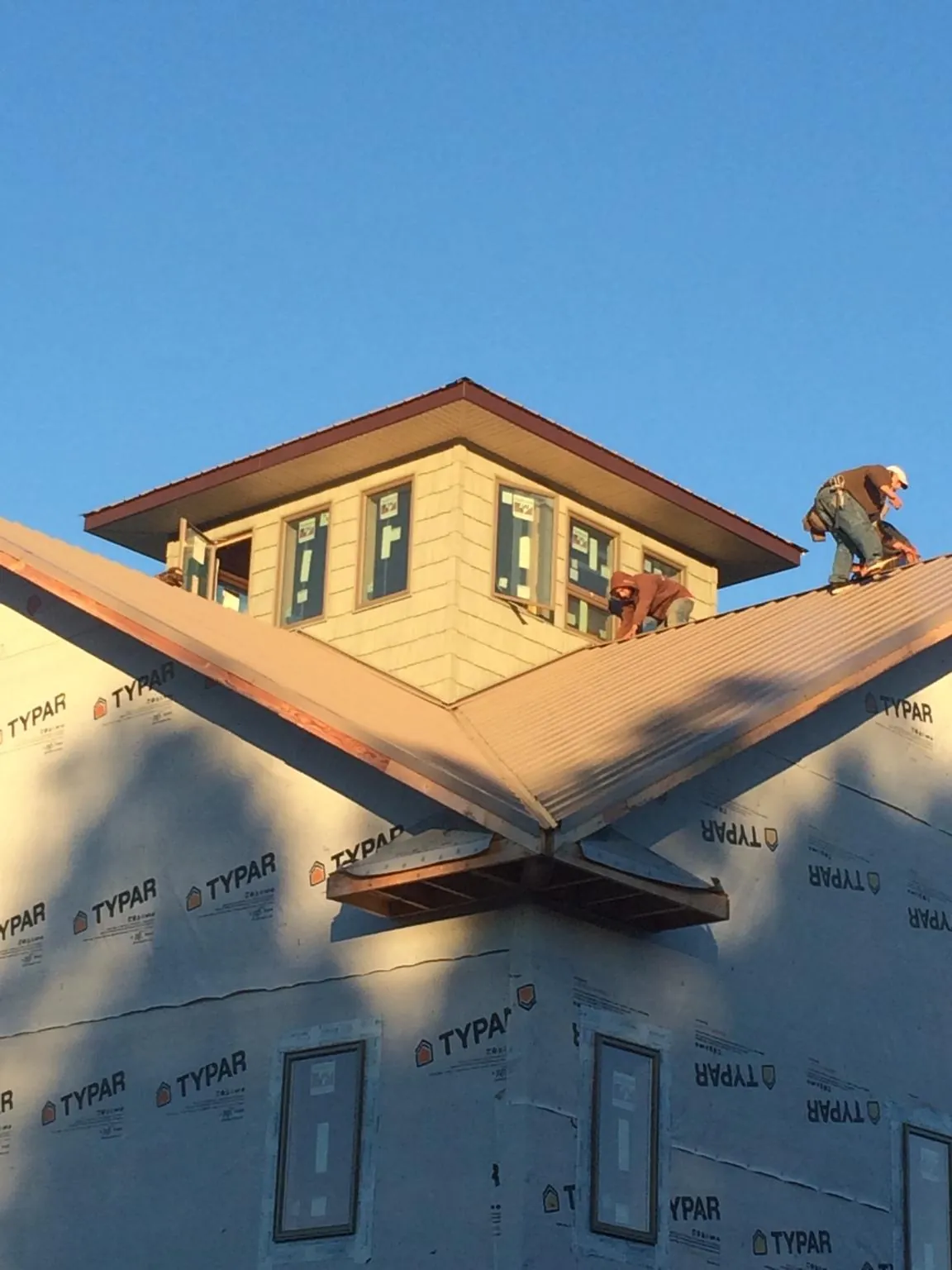 Roofers working around a rooftop cupola on a new metal roof at sunset — Roof Waterproofing in Rossburg by Roofing Brothers